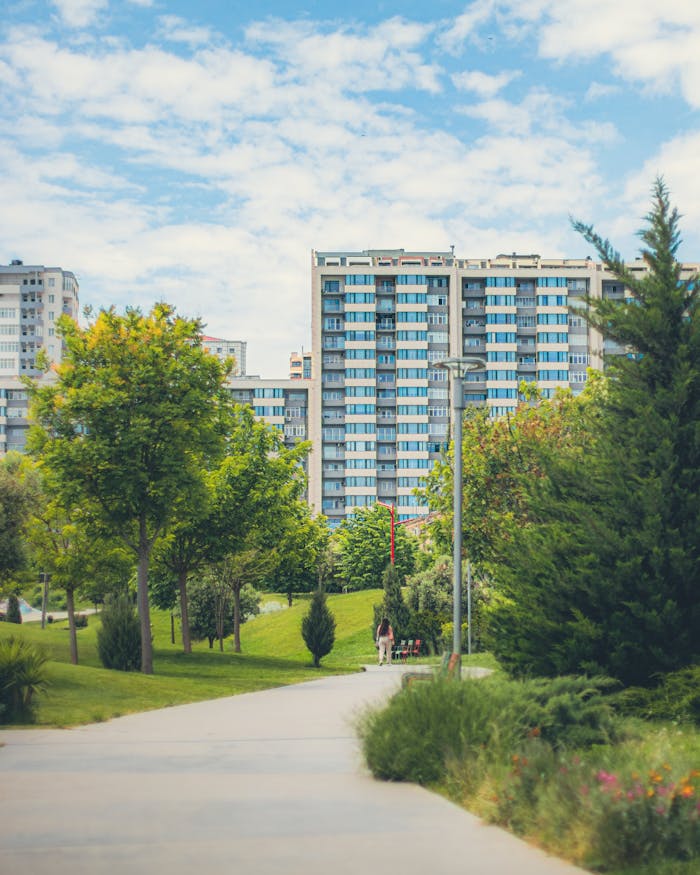 Lush green urban park with high-rise buildings in the background, captured on a sunny day.